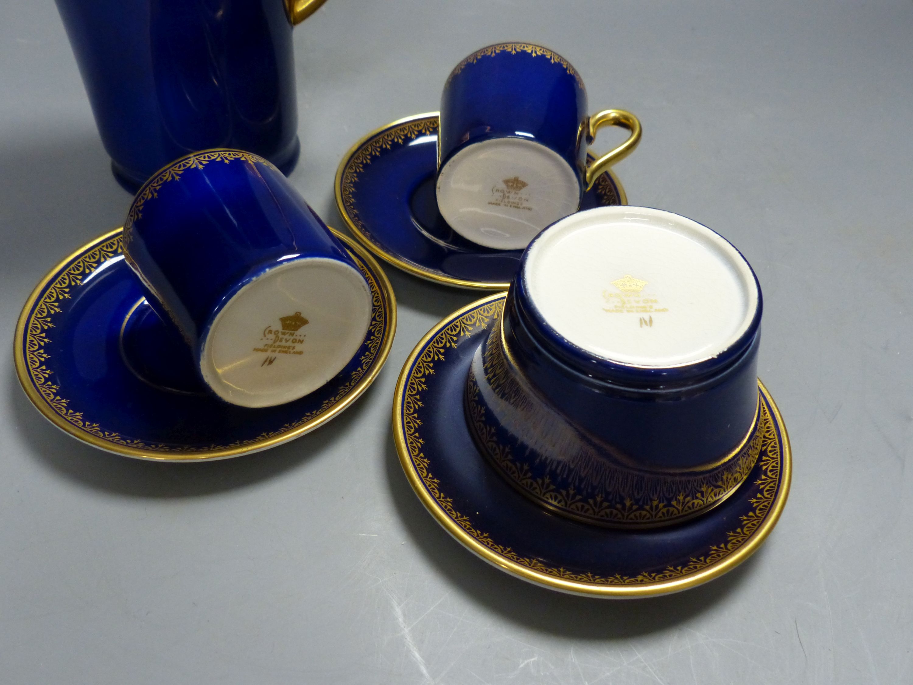 A Crown Devon Fieldings part coffee service, cobalt blue with gilt interiors and patterned rims,